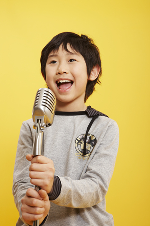 Young Aisn boy posing in a studio with microphoneの写真素材