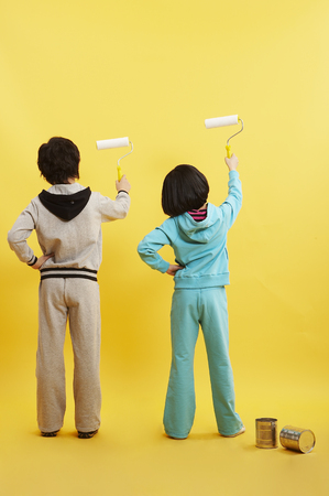 Young Asian boy and girl posing in a studio with paint rollersの写真素材