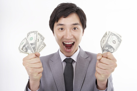 Asian man in suit posing in a studio with money billsの写真素材