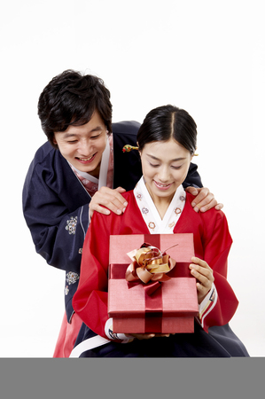 Asian couple wearing traditional korean costume posing in a studio with giftboxの写真素材