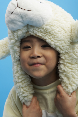 Close up shot of Young Asian boy wearing sheep costume posing in a studioの写真素材