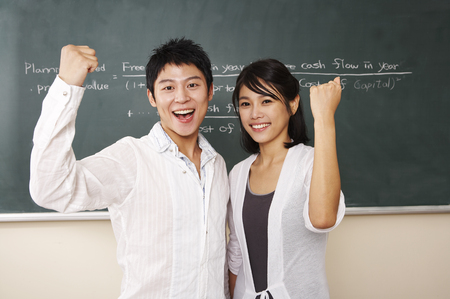 Asian college couple posing in a classroom with hand gestureの写真素材