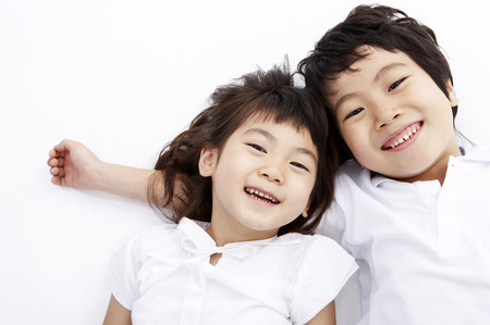 Young Asian boy and girl posing together in a studio as lying on backの写真素材