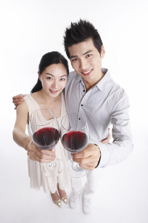Asian couple posing in clear white studio with wineの写真素材