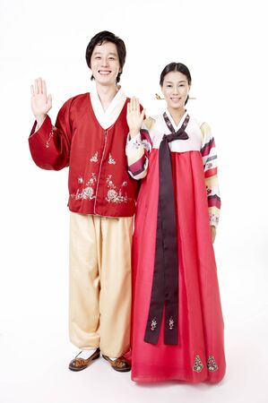 Asian couple wearing traditional korean costume posing in a studio with hand gestureの写真素材