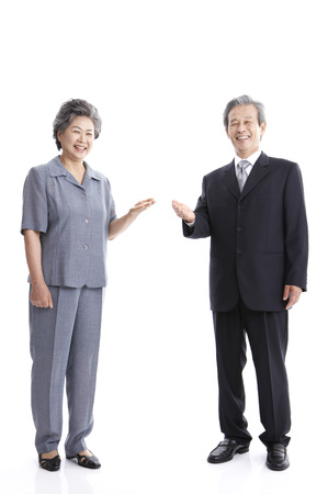 Asian elderly couple wearing suits posing in a studio with gestureの写真素材