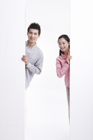 Asian couple posing in clear white studio with white wallの写真素材