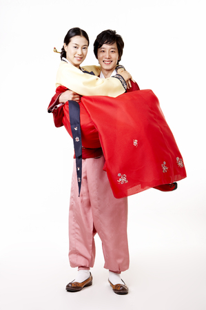 Asian husband carrying wife as wearing korean costume isolated in whiteの写真素材