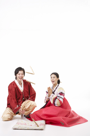 Asian couple wearing traditional korean costume posing in a studio as playing traditional game, yutの写真素材