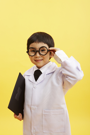 Young Asian boy wearing doctor robe posing in a studio with patient chartの写真素材