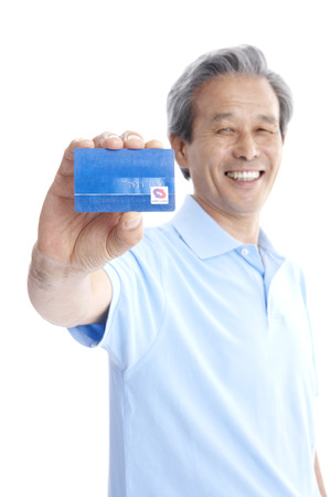 Male Asian elderly posing in a studio with credit cardの写真素材
