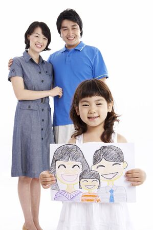 Asian parents and a daughter posing in a studio with a drawingの写真素材