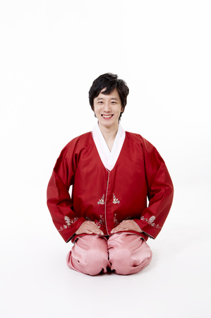 Korean man wearing traditional costume posing in a studio as sitting on kneewsの写真素材