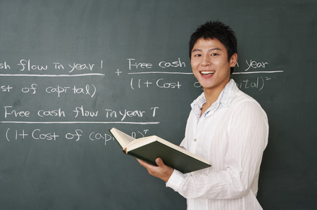 Male Asian college student posing in a classroom as standing in front of black boardの写真素材
