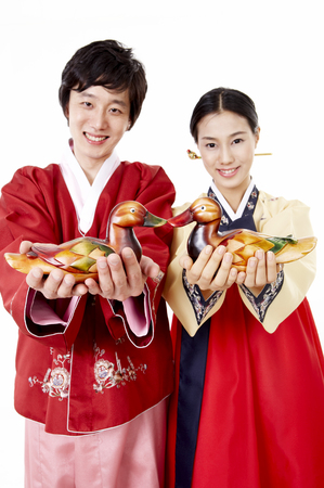 Asian couple wearing traditional korean costume posing in a studio with a pair of mandarin ducksの写真素材