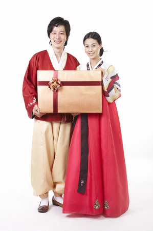 Asian couple wearing traditional korean costume posing in a studio with giftboxの写真素材
