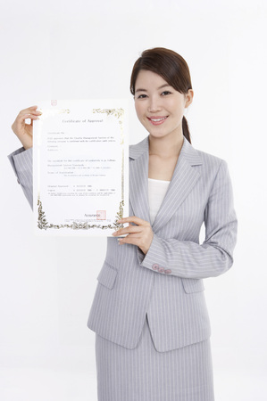 Asian business woman in suit posing in a studio with certificateの写真素材