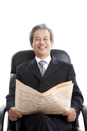 Male Asian elderly in suit posing in a studio with English newspaperの写真素材