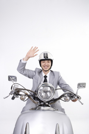 Asian business man in suit posing in a studio as riding a motorcycleの写真素材