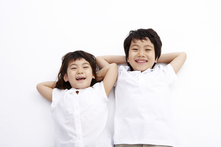 Young Asian boy and girl posing together in a studio as lying on backの写真素材