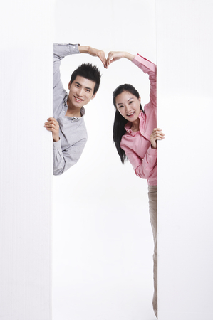 Asian couple posing in clear white studio with white wallの写真素材