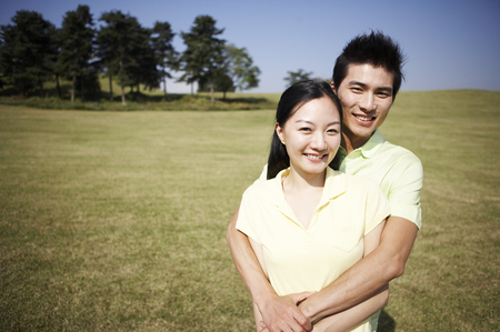 Asian couple posing together in a green fieldの写真素材