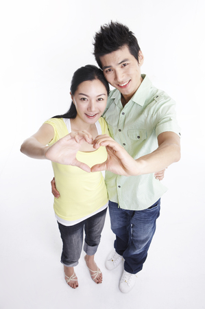 Asian couple posing in clear white studio with hand gestureの写真素材