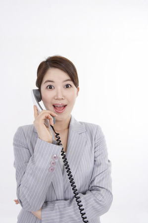 Asian business woman in suit posing in a studio speaking on the landline telephoneの写真素材