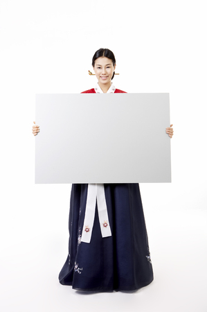 Korean woman wearing traditional costume posing in a studio with message boardの写真素材