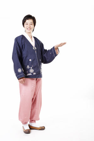Korean man wearing traditional costume posing in a studio with hand gestureの写真素材
