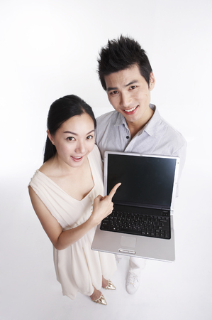 Asian couple posing in clear white studio with laptopの写真素材