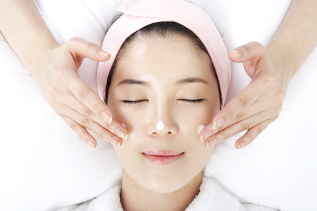Close up shot of face of woman receiving massages with masseuse handsの写真素材