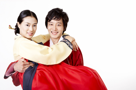 Asian husband carrying wife as wearing korean costume isolated in whiteの写真素材