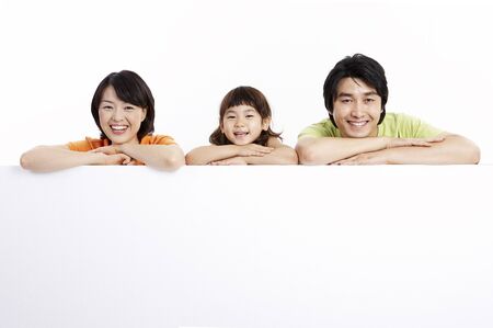 Asian parents and daughter posing in a studio as lying on stomachの写真素材