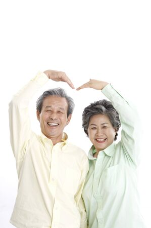 Asian elderly couple posing in a studio with hand gestureの写真素材
