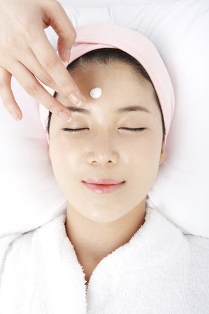 Close up shot of face of woman receiving massages with masseuse handsの写真素材