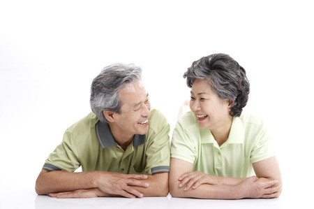 Asian elderly couple posing in a studio as lying on stomachの写真素材