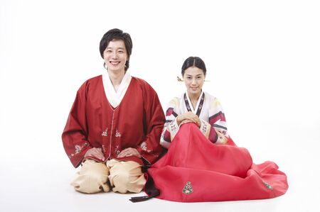 Asian couple wearing traditional korean costume posing in a studio as sitting on floorの写真素材