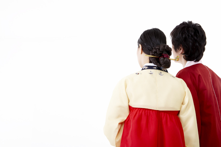 Back shot of Asian couple wearing traditional korean costume posing in a studioの写真素材