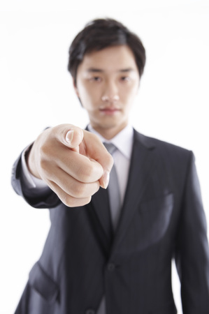 Asian business man in suit posing in a studio with pointing fingerの写真素材