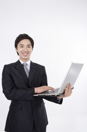 Asian business man in suit posing in a studio with laptopの写真素材