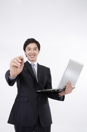 Asian business man in suit posing in a studio with laptopの写真素材
