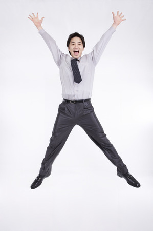 Asian business man in suit posing in a studio as jumpingの写真素材
