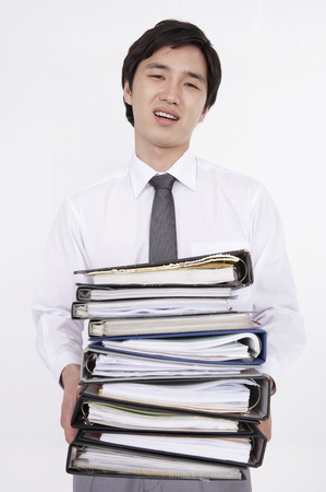 Asian business man in suit posing in a studio with file foldersの写真素材