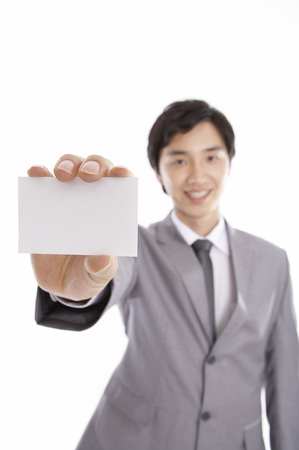 Asian business man in suit posing in a studio with empty white namecardの写真素材