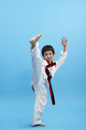 Young Asian boy wearing taekwondo uniform posing in a studioの写真素材