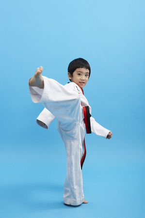 Young Asian boy wearing taekwondo uniform posing in a studioの写真素材