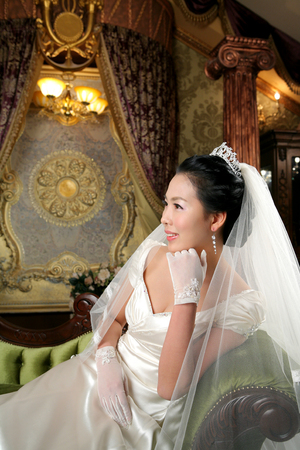 Asian bride in wedding dresses posing in antique studio as sitting downの写真素材