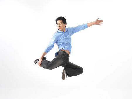 Asian man in jumping pose in a studioの写真素材