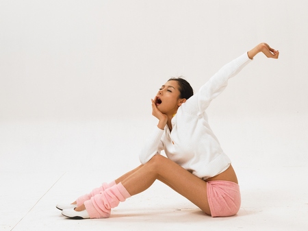 Asian woman fashion model posing in a studio as wearing pink and white yoga outfit with leg warmersの写真素材
